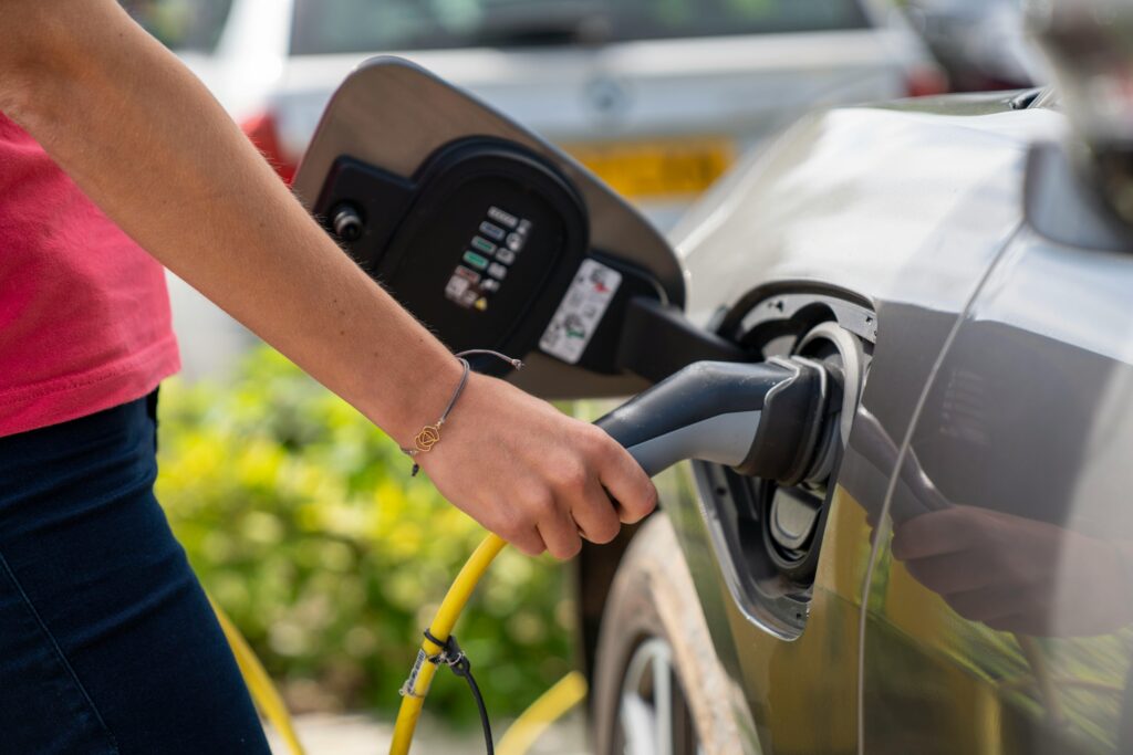 service-3 Close-up of a person plugging in an electric car at a charging station outdoors.